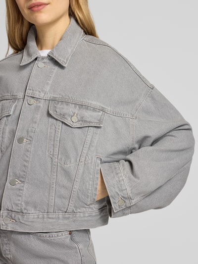 Frauenmodel trägt Oversized Jeansjacke aus Lyocell-Baumwoll-Mix Modell 'PAASITHE' von Armedangels in hellem Denim, Nahaufnahme Oberkörper.
