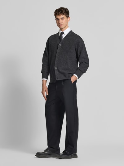 Männermodel trägt Straight Fit Stoffhose mit Bundfalten von ANNARR in Schwarz, kombiniert mit Hemd und Strickjacke, Ganzkörperansicht von vorne. Herren Stoffhose, Knopf- und Reißverschluss, Eingrifftaschen, Leistentaschen am Gesäß, Innenbeinlänge 81 cm, Bundweite 48 cm.