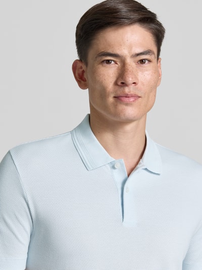 Męski model nosi Regular Fit Poloshirt aus Baumwoll-Mix Modell 'PARLAY 240' od BOSS, jednolity kolor, krój regular fit, bawełniana faktura, aplikacja z logo, kołnierzyk polo, dekolt w serek, krótki rękaw; zbliżenie na górną część ciała.