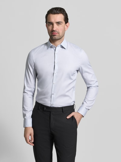 Męski model ma na sobie Slim Fit Businesshemd mit Kentkragen von OLYMP No. Six, bawełniany elastyczny miks, długość 81 cm, szerokość ramion 43 cm, długość rękawa 67 cm, koszula z długim rękawem, sportowe mankiety, cała lista guzików, jasnoszary kolor, gładka faktura, pełny widok od przodu.