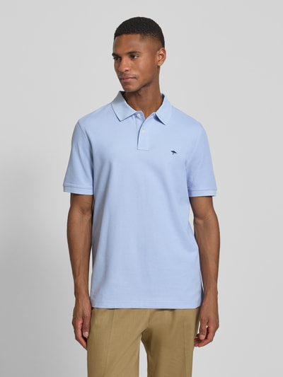 Męskki model nosi Regular Fit Poloshirt mit Logo-Stitching von Fynch-Hatton, jasnoniebieska bawełna, krótki rękaw, polokołnierzyk, krój regular fit, długość pleców w rozmiarze M: 70 cm, całościowy widok z przodu.
