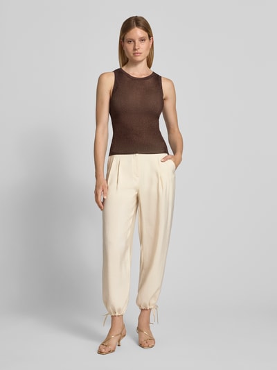 Modelka kobieca ma na sobie spodnie 'Relaxed Fit Hose mit eingefassten Beinabschlüssen' od Christian Berg Woman Selection, mieszanka modalu, krój relaxed fit, zakończenia nogawek: obszyte, zakładki w pasie, kieszenie z tyłu, zapięcie na guzik i zamek błyskawiczny, szerokość w rozmiarze 36: 40 cm, długość wewnętrzna nogawki w rozmiarze 36: 70 cm, widok całej sylwetki z przodu.