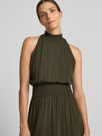 Frauenmodel trägt Midikleid aus Viskose-Mix von Samsøe Samsøe in Olivgrün mit Smok-Detail, Stehkragen, taillierter Passform, Nahaufnahme Oberkörper.