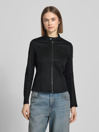 Modelka kobieca nosi czarną Slim Fit Bikerjacke mit Label-Detail Modell 'Lynn' von G-Star Raw, bawełna z elastanem, stehkaptur, zamek, widoczne tekstury, szerokość w rozmiarze S: 38 cm, długość tyłu: 53 cm, szerokość klatki: 41 cm, długość rękawa: 61 cm, krój slim fit, ujęcie całej sylwetki z przodu