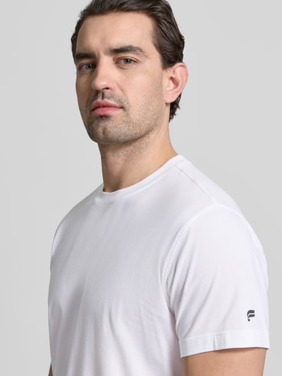 Męski model nosi Slim Fit T-Shirt mit Rundhalsausschnitt von Fabletics, biały, elastyczna mieszanka bawełny z modalem, krój slim fit, krótki rękaw, długość tyłu w rozmiarze M: 68 cm, widok na górną część ciała z przodu.