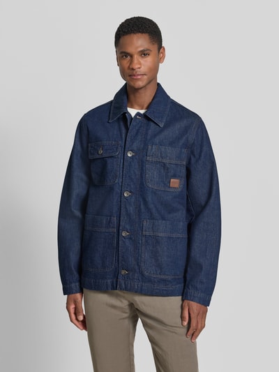 Männermodel trägt Regular Fit Jeansjacke aus reiner Baumwolle Modell 'WORK' von GANT, blaue Denim-Optik, aufgesetzte Taschen, Umlegekragen, Ganzkörperansicht von vorne. Rückenlänge 71 cm, Schulterbreite 44 cm, Brustweite 51 cm, Ärmellänge 65 cm.