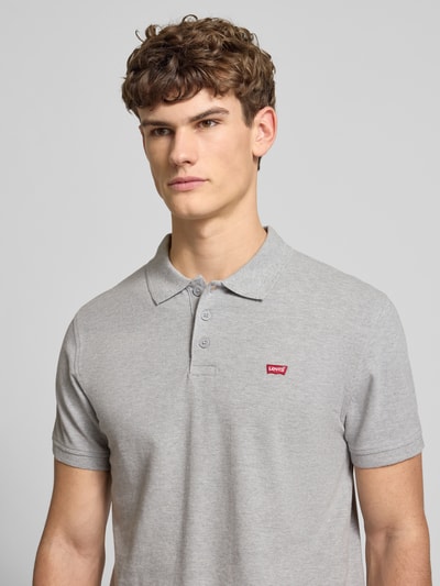 Męski model nosi Poloshirt mit Label-Detail od Levi's®, szary, bawełna, regular fit, krótka listwa, kołnierzyk, zbliżenie na górę ciała.
