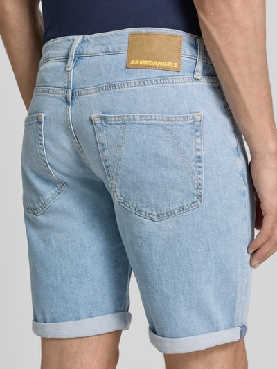 Männermodel trägt Slim Fit Jeansshorts aus Baumwoll-Mix Modell 'NAAILO' von Armedangels, hellblauer Denim mit Label Patch, 5-Pocket, Ganzkörperansicht Rückansicht