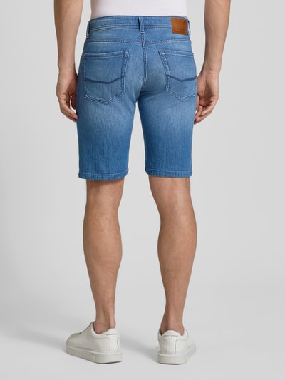 Männermodel trägt Regular Fit Jeansshorts mit Eingrifftaschen Modell 'Sisteron' von Pierre Cardin, Baumwoll-Elasthan-Mix, Rückenansicht. Herren Jeansshorts, Bundweite 40 cm, Innenbeinlänge 27 cm, mittleres Blau, glatte Struktur. Ganzkörperansicht Rückansicht.