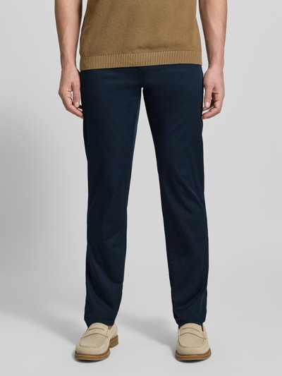 Męski model nosi Slim Fit Stoffhose mit Lyocell-Anteil Modell 'Cadiz' von BRAX, elastyczna mieszanka bawełny i lyocellu, krój slim fit, 5 kieszeni, kolor granatowy, szerokość w rozmiarze 32/32: 107 cm, długość wewnętrzna nogawki: 81 cm, zapięcie na guzik i zamek błyskawiczny, widok całej sylwetki z przodu.