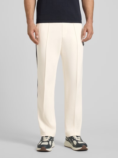 Männermodel trägt Sweatpants mit Label-Patch und elastischem Bund von ARMANI EXCHANGE, Relaxed-Fit, Baumwoll-Mix mit Stretch-Anteil, Längsnähte, cremefarben, Detailaufnahme Beine von vorne.