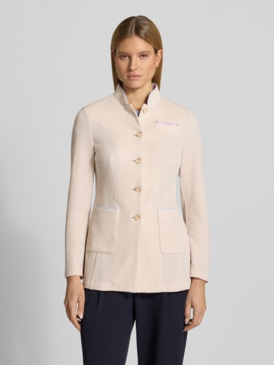 Modelka kobieca nosi Blazer mit Stehkragen und Brusttasche od WHITE LABEL, mieszanka materiałów z dodatkiem wiskozy, taliowany krój, stójka, listwa guzikowa, nakładana brustasza, nakładane wpuszczane kieszenie, długość tyłu w rozmiarze 36: 55 cm, szerokość w rozmiarze 36: 44 cm, długość rękawów w rozmiarze 36: 62 cm, jasny beżowy kolor, wykończenie o strukturze tkaniny, widok całej sylwetki z przodu
