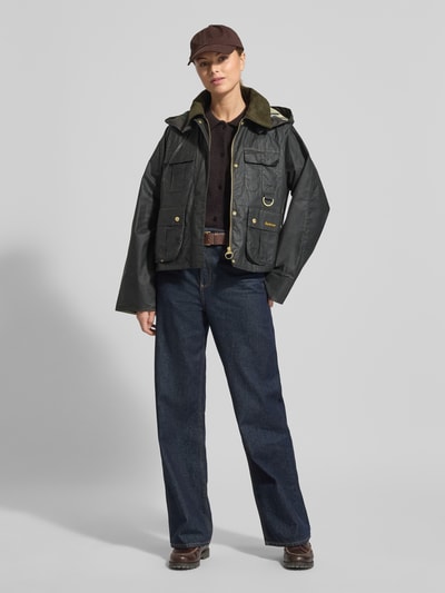 Kobiece modelka nosi Regular Fit Funktionsjacke aus reiner Baumwolle Modell 'LIZA' von Barbour, ciemne kolory, metalowe akcenty, naszywane kieszenie, tkanina o gładkiej, woskowanej teksturze, cała sylwetka z przodu