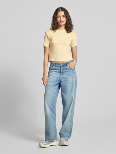 Modelka kobieca nosi T-Shirt mit Rundhalsausschnitt od Topshop z bawełny, krój taliowany, okrągły dekolt, krótki fason, długość tyłu w rozmiarze S: 47 cm, jasny beż, gładka faktura, pełny widok z przodu