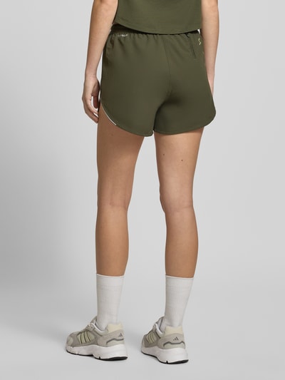 Frauenmodel trägt PUMA x HYROX - Shorts mit Label-Print von PUMA, lockerer Schnitt, elastischer Bund, olivgrün, Ganzkörperansicht Rückansicht.