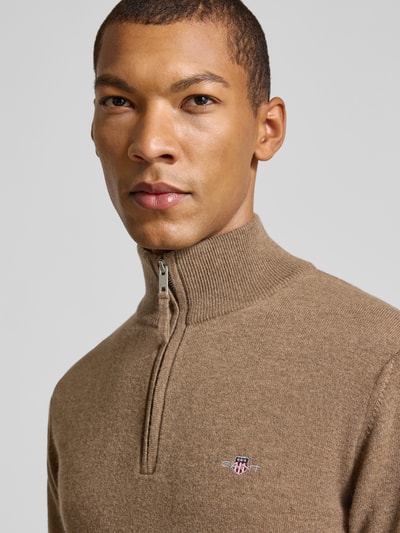 Männermodel trägt Pullover aus reiner Wolle von GANT in Braun, Feinstrick, hochgeschlossener Troyer-Kragen, Nahaufnahme Oberkörper.