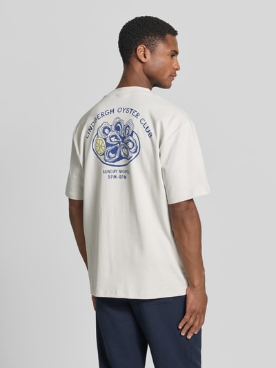 Männermodel trägt Oversized T-Shirt mit Label-Print von Lindbergh in heller Farbe aus Reine Baumwolle, Rückenlänge bei Größe M: 70 cm, Ganzkörperansicht Rückansicht.