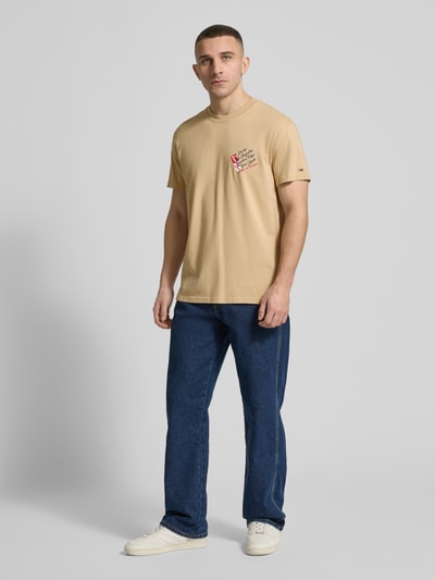Männermodel trägt Regular Fit T-Shirt aus reiner Baumwolle von Tommy Jeans in Optik: Unifarben mit Label-Print, Jersey, Ganzkörperansicht von vorne.