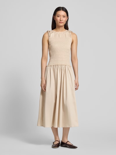 Frauenmodel trägt Midikleid mit Smok-Detail von Comma, Baumwoll-Mix, Taillierte Passform, Rundhalsausschnitt, Ärmelloses-Design, sandfarben, Ganzkörperansicht von vorne.