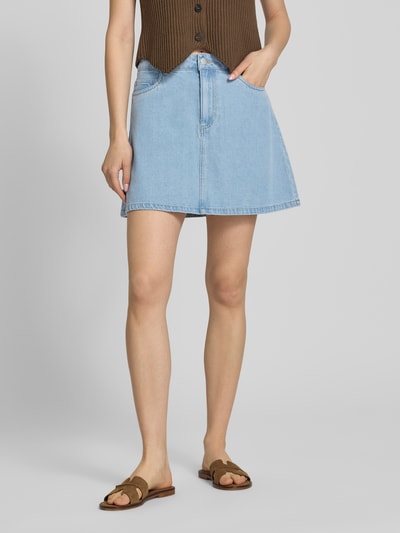 Vrouwenmodel draagt A-lijn jeansrok uit katoenmix met viscose, denimlook in lichtblauw, 5-pocketmodel, Pieces model 'ABBI', minilengte, knoop- en ritssluiting, materiaalverwerking twill, detailopname onderlichaam, voorkant.