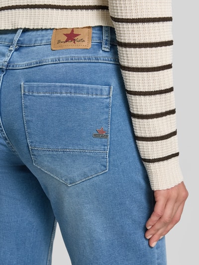 Kobieta nosi Straight Fit Jeans in 7/8-Länge Modell 'Ana' von Buena Vista, mieszanka bawełny z dodatkiem streczu, długość 7/8, szerokość w rozmiarze S: 39 cm, długość wewnętrzna nogawki w rozmiarze S: 69 cm, widoczne jasnoniebieskie denimowe kolory i gładka tekstura, detailaufnahme tylnej kieszeni.