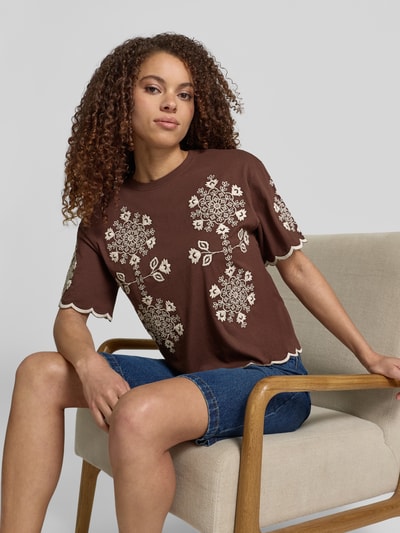 Vrouwenmodel draagt T-Shirt met Wellensaum und Motiv-Stitching van Jake*s Casual in bruin met witte stiksels, rechte fit, puur katoen, rond hals, detail op mouwen en zoom, voorkant, halve lichaamsopname.