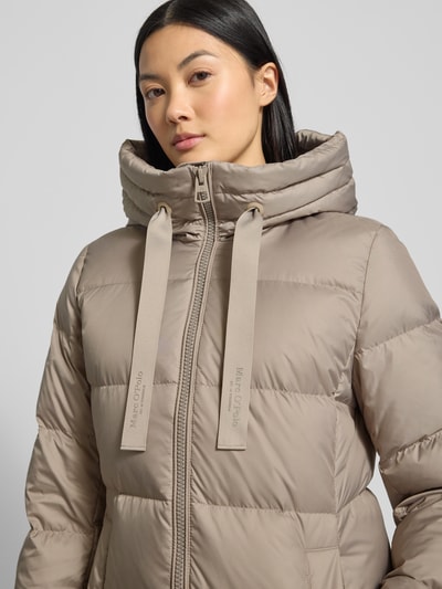 Vrouwenmodel draagt Shaped Fit Daunenmantel met Kapuze van Marc O'Polo in effen beige, langarm met tunnelkraag, close-up bovenlichaam.