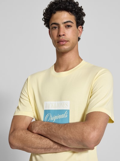 Männermodel trägt T-Shirt mit Statement-Print Modell 'RHYERES' von Jack & Jones aus gewachster Baumwolle in Gelb, Nahaufnahme Oberkörper.