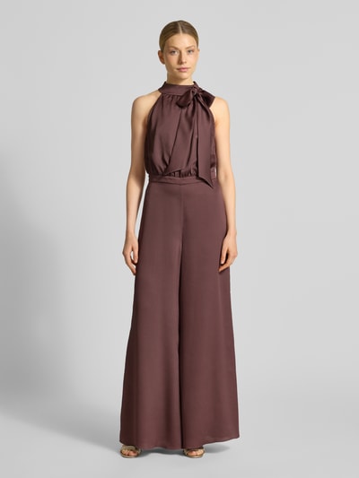 Kobiece modelka nosi Jumpsuit mit Zierschleife od Swing, brązowy, strukturalny wzór, taliowany krój slim fit, bez rękawów, materiał elastyczny, szerokie nogawki, szerokość w rozmiarze 36: 37 cm, długość całkowita: 150 cm, długość tyłu: 43 cm, długość wewnętrzna nogawki: 82 cm, widok całej sylwetki z przodu.