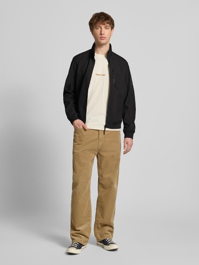 Männermodel trägt Regular Fit Bomberjacke mit Stehkragen Modell 'Parker' von Jack & Jones in Schwarz, Softshell, Ganzkörperansicht von vorne.