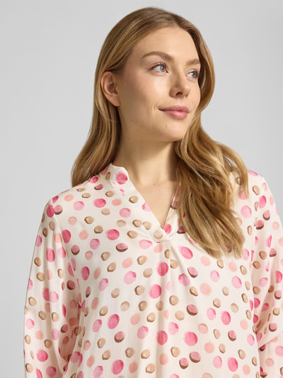 Frauenmodel trägt Regular Fit Bluse aus reiner Viskose Modell 'Josy' von Zabaione, rosa Punkte auf cremefarbenem Stoff, Nahaufnahme Oberkörper, Tunika-Kragen und elastische Ärmelabschlüsse, Rückenlänge bei S: 62 cm, Ärmellänge bei S: 56 cm.
