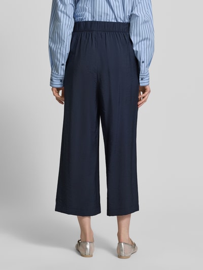 Modelka kobieca nosi Loose Fit Culotte aus Viskose-Mix od s.Oliver RED LABEL, granatowy kolor, popelina, kieszenie boczne, widok całej sylwetki od tyłu.