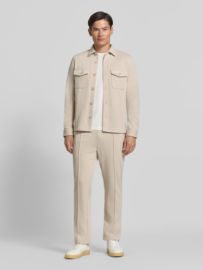 Männermodel trägt Straight Fit Hose mit Baumwoll-Anteil Modell 'Parker' von MCNEAL in Beige, glatte Textur, Ganzkörperansicht von vorne. Material-Mix, Elastischer Bund, Gesäßtasche, Innenbeinlänge 73 cm bei Größe M.
