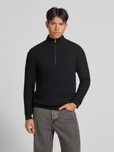 Männermodel trägt schwarzen Regular Fit Pullover aus reiner Baumwolle Modell 'TONY' von ONLY & SONS, Ganzkörperansicht von vorne.