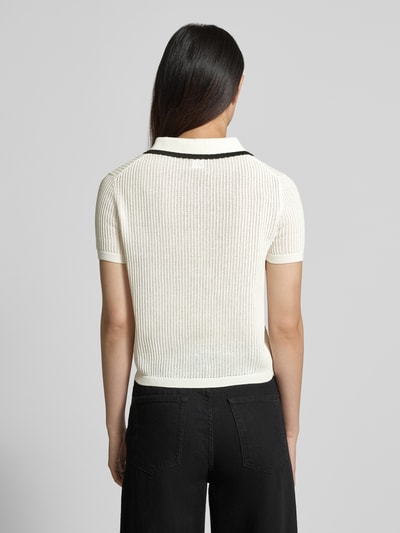 Frauenmodel trägt Regular Fit Strickshirt aus reiner Baumwolle Modell 'SLYSA' von HUGO in Optik: Unifarben mit Struktur-Muster, Logo-Stitching, Kontraststreifen, Ärmelform: Kurzarm, Ärmelabschluss: Gerippt, Rumpfabschluss: Gerippt, Materialverarbeitung: Strick, Ganzkörperansicht Rückansicht.