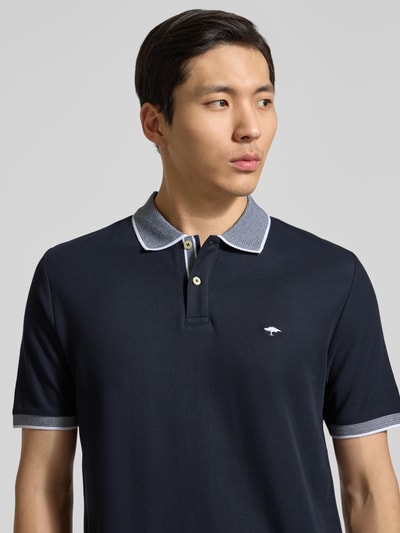 Mężczyzna nosi Modern Fit Poloshirt mit Stitching od Fynch-Hatton, granatowa bawełna, kołnierzyk polo, guzik, detal na kołnierzu, widok na górną część ciała z przodu, długość tyłu w rozmiarze M: 65 cm.