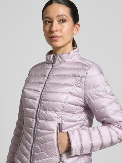 Frauenmodel trägt Steppjacke mit Stehkragen von Gil Bret in Helllila, mit Zweiwege-Reißverschluss, Reißverschlusstaschen, Körpernahe Passform, Rückenlänge 56 cm, Schulterbreite 39 cm, Brustweite 47 cm, Ärmellänge 66 cm, Nahaufnahme Oberkörper.