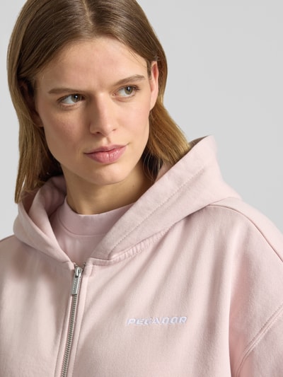 Frauenmodel trägt Oversized Sweatjacke mit Label-Stitching Modell 'CLARITA' von Pegador, Baumwoll-Mix, Reißverschluss, Nahaufnahme Oberkörper.