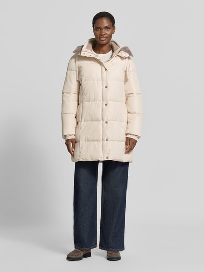 Frauenmodel trägt Steppmantel mit abnehmbarer Kapuze von White Label in Beige, seitliche Reißverschlusstaschen, Gerade geschnitten, Ganzkörperansicht von vorne.