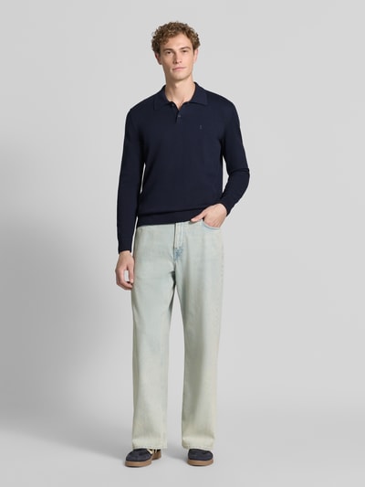 Mężczyznamodel nosi ciemnogranatową koszulkę polo Slim Fit Poloshirt aus reiner Baumwolle von ARMEDANGELS oraz jasnoniebieskie spodnie, gładka faktura, Ganzkörperansicht von vorne.