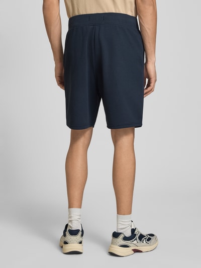 Männermodel trägt Straight Fit Shorts mit Strukturmuster von G-Star Raw in Dunkelblau, Elastischer-Material-Mix, Logo-Detail, Ganzkörperansicht Rückansicht.
