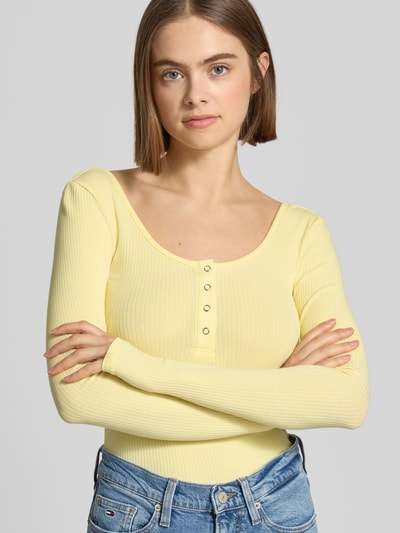 Modelka kobieca nosi Slim Fit Langarmshirt aus Baumwoll-Mix Modell 'KITTE' od Pieces w żółtym kolorze, prążkowana faktura, gładki wzór, widok z przodu, zbliżenie na górną część ciała.
