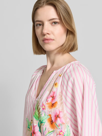 Frauenmodel trägt Bluse mit Tunikakragen und elastischen Ärmelabschlüssen von Emily Van den Bergh in Rosa mit Streifen und Blumen, Nahaufnahme Oberkörper. Reine Baumwolle, gerader Schnitt.