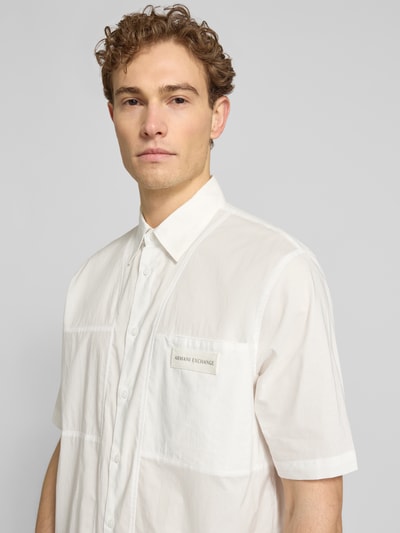 Männermodel trägt Boxy Fit Freizeithemd mit Label-Patch von ARMANI EXCHANGE, reine Baumwolle, weiß, Kentkragen, Nahaufnahme Oberkörper.