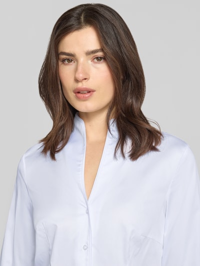 Vrouwenmodel draagt 'Hemdbluse mit Stehkragen und Sportmanschetten' van Christian Berg Woman in lichtblauw, rechte fit, katoenmix met stretch, staande kraag, knoopsluiting, sportmanchetten, detailopname bovenlichaam.