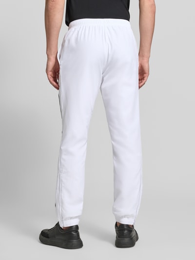 Männermodel trägt weiße Regular Fit Trainingshose mit Logo-Patch von Lacoste, Herren Trainingshose von Lacoste Sport, Ganzkörperansicht Rückansicht.
