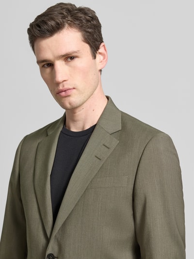 Männermodel trägt Regular Fit Blazer mit Logo-Patch Modell 'Justin' van Tiger Of Sweden in olijfgroen, puur katoen, borstzak, reverskraag, 2-knoopsluiting, detailaufnahme bovenlichaam, context heren blazer, ruglengte maat 50: 79 cm, schouderbreedte: 38 cm, mouwlengte: 66 cm.