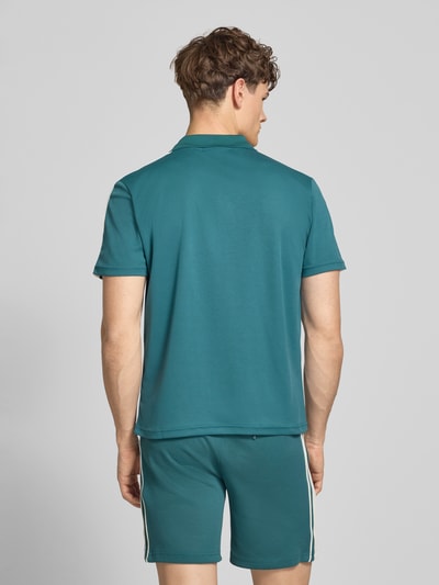 Männermodel trägt Regular Fit Poloshirt mit Logo-Stitching Modell 'EGEO' von SERGIO TACCHINI in Petrol, Kurzarm, Rückenlänge 66 cm, Ganzkörperansicht Rückansicht.