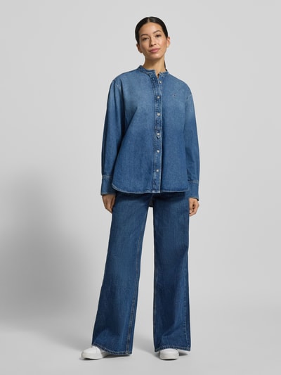 Vrouwenmodel draagt Relaxed Fit Jeansblouse uit katoen-lyocell-mix van Tommy Hilfiger in denimlook met gestikt logo, doorlopende knoopsluiting, maokraag, lange mouw met manchet, afgeronde rompzoom, voorkant, geheellichaamsaanzicht.