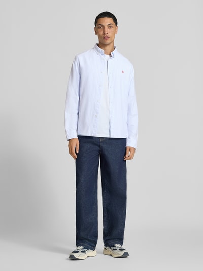 Männermodel trägt Regular Fit Freizeithemd aus reiner Baumwolle von REVIEW, hellblaue Farbe, Knopfleiste, Button-Down-Kragen, Langarm, dezente Struktur, Ganzkörperansicht von vorne.